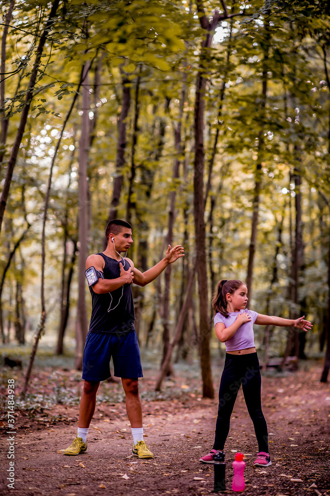 Fototapeta premium Young man and girl are training in the park