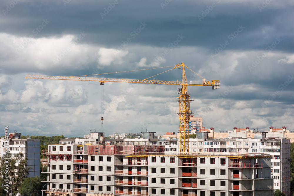 Construction crane on construction site in city on cloudy sky background
