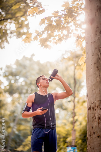 Young sportsman in nature, drinking water.