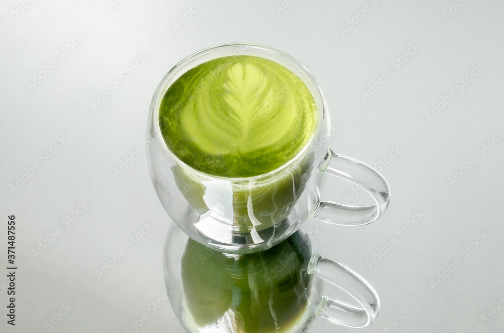 Single-cup of a fresh matcha tea reflected on the glass Single-cup of a fresh matcha tea reflected on the glass