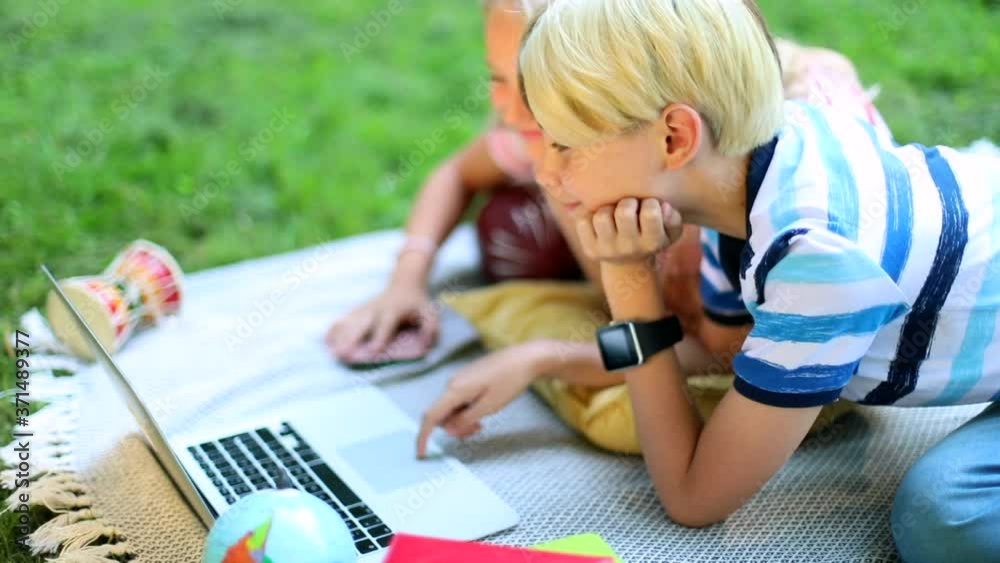 Smart fashion kids using notebook resting in sunny green park outside. Learning online with friends. High school education concept. Freelance lifestyle. Children communication. Summer leisure.Internet Smart fashion kids using notebook resting in sunny green park outside. Learning online with friends. High school education concept. Freelance lifestyle. Children communication. Summer leisure.Internet