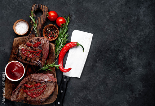  Two grilled beef monster steaks with spices for halloween on stone background with copy space for your text