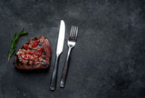 grilled beef steak with spices, knife and fork for halloween on stone background with copy space for your text