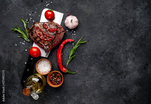 Grilled beef steak with spices on a butcher's knife for Halloween on stone background with copy space for your text