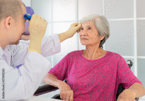 asian doctor use flashlight screening eyes of old asian patient, vision and cataract screening, elderly healthcare check up in hospital