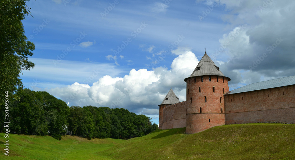 Towers and walls of ancient Great Novgorod Kremlin with some clouds in light blue sky in summer day. Veliky Novgorod, Russia. Historical travelling. Panoramic view 