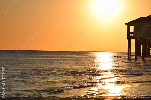 Beach house silhouette by ocean sunset