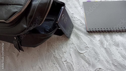 Backpack black color with school supplies, sanitizer and medical protective mask, purse and apple, stop motion animation on a white background. Back to school or work after quarantine concept.