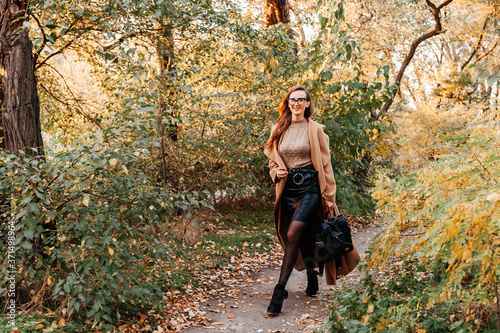 beautiful girl in a coat, black skirt and jacket autumn walks in glasses © Олег Блохин
