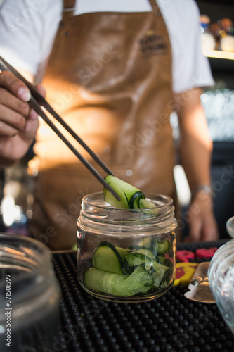 Bartender sosteniendo rollito de pepino para decorar bebida  photo