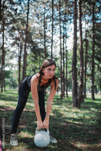 Young Caucasian woman exercising with kettle bell outdoors