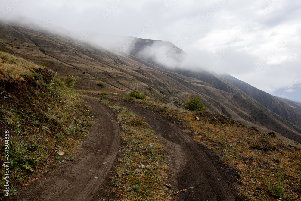 Moon road. Mountain road in cloudy weather. Green mountains in the fog Moon road. Mountain road in cloudy weather. Green mountains in the fog