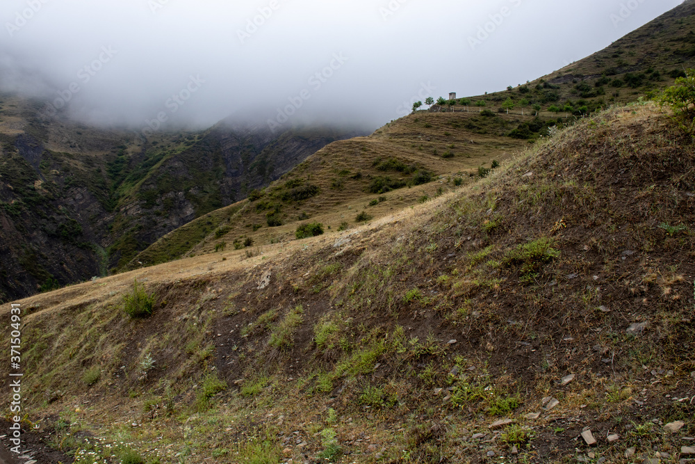 Fragment of a high altitude road in the mountains.Location Dagestan, Russia. Caucasus mountains in cloudy weather. The Caucasus mountains in cloudy weather in the fog