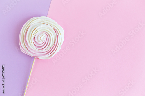 Tender  meringue on a pink and violet pastel background. Concept for holiday greeting card or background.
