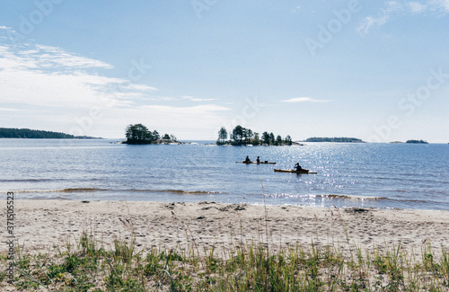 Silhouettes of kayaks at the sandy beach on lake Ladoga on a Sunny summer day