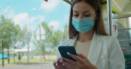 Young woman in protective medical face mask in a public transport using smartphone. Young girl usig app on a smartphone. photo