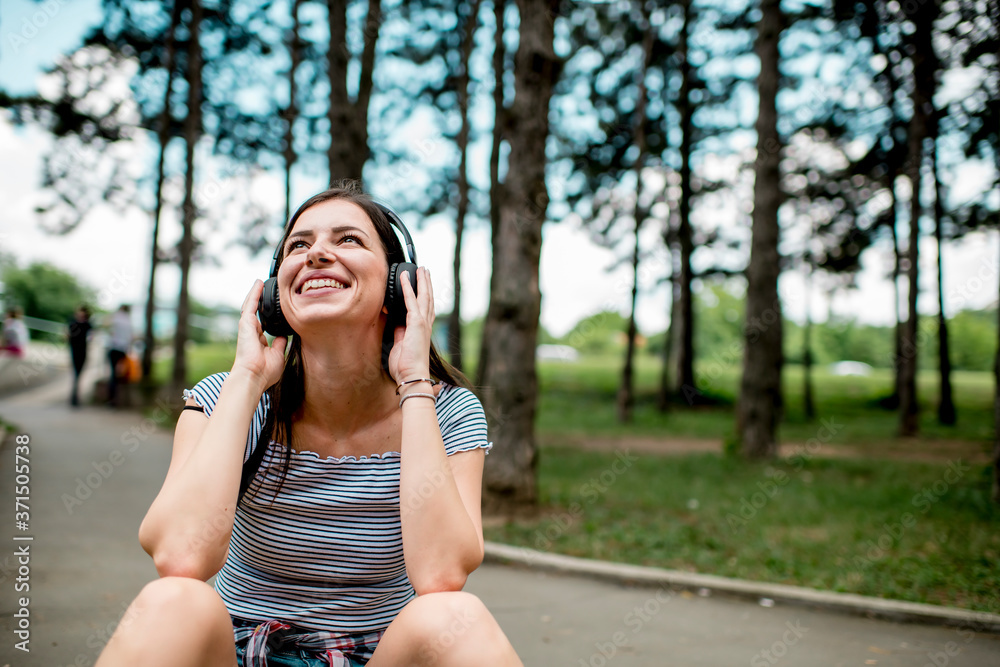 Smiling girl listening music in the park  