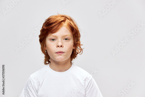 Cute red-haired child in a white t-shirt cropped view look ahead 