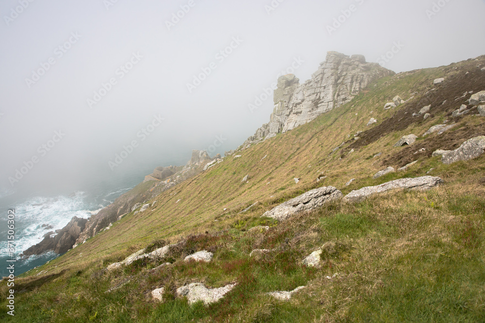 The rocky coastline of the island of Lundy emerging from the fog, The Bristol Channel, Devon, UK