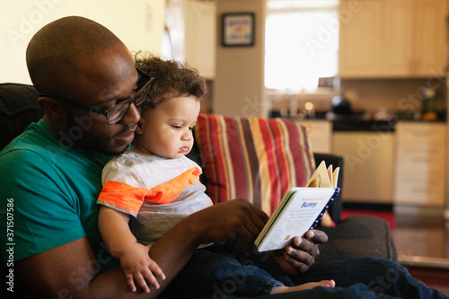 Father reading to baby on sofa photo