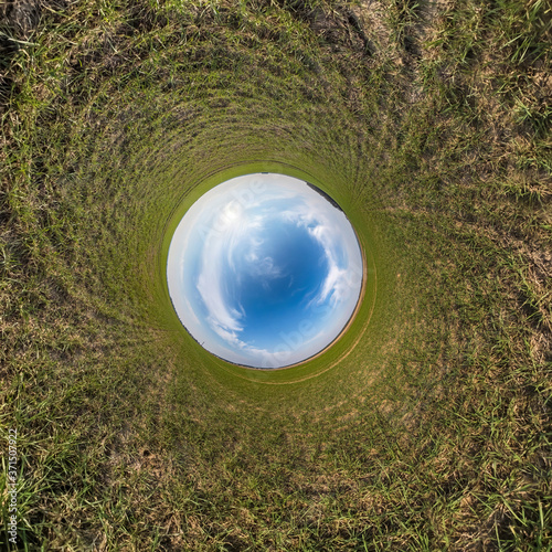 Inversion of little planet transformation of spherical panorama 360 degrees. Spherical abstract aerial view on field with awesome beautiful clouds. Curvature of space.