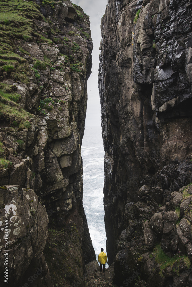 Rear view of man standing between two cliffs Rear view of man standing between two cliffs