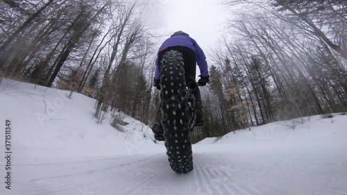 Fat bike in winter. Fat biker riding bicycle in the snow in winter. Close up action shot of fat tire bike wheels in the snow. Woman living healthy active winter sports lifestyle. Shot on action camera photo