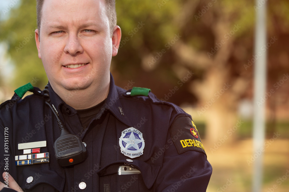 Portrait of Police officer standing outside with arms crossed looking towards camera smiling Portrait of Police officer standing outside with arms crossed looking towards camera smiling