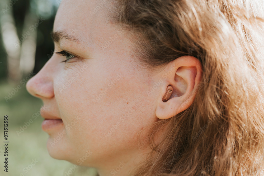 small intra channel hearing aid in the ear of a woman