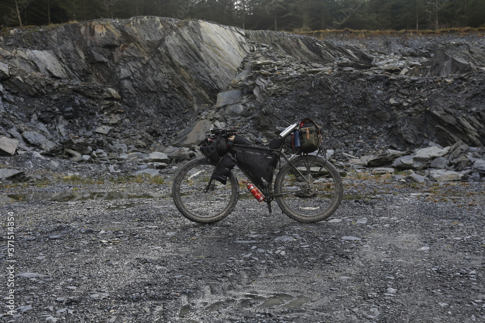 Grey rocks and my bikepacking rig in a Welsh quarry. 