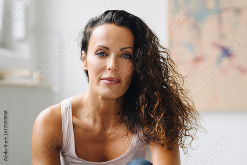 Close-up of mid adult woman with wavy hair sitting at home