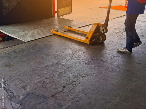 Worker driving forklift loading and unloading shipment carton boxes and goods on wooden pallet from container truck to warehouse cargo storage in logistics and transportation industrial 