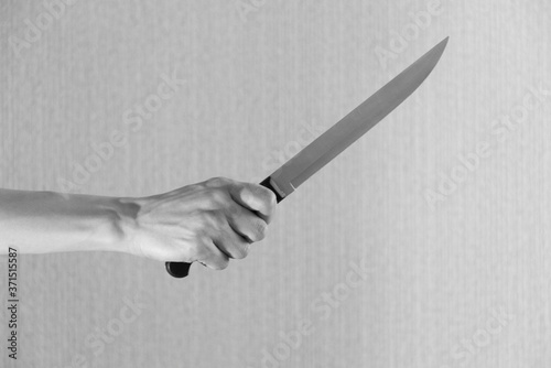 Hand is holding a kitchen kinfe isolated on a gray background