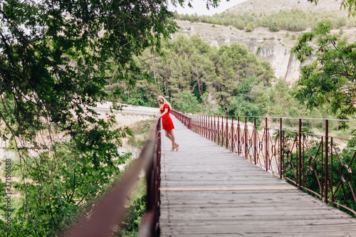 Woman wearing red dress on Saint Paul Bridge in Cuenca, Spain photo
