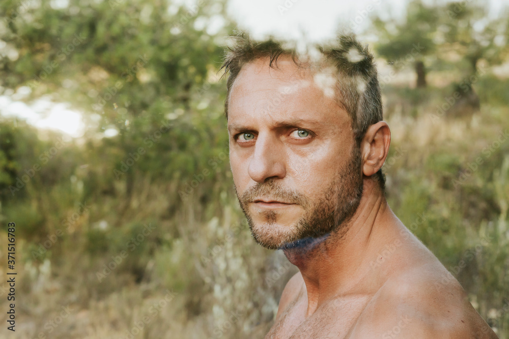 Close-up of shirtless handsome man against trees in forest seen through glass