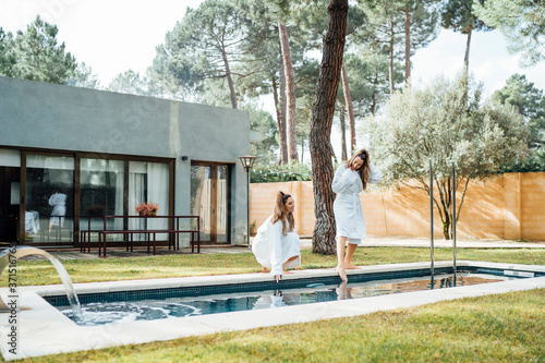 Twin sisters enjoying at poolside in tourist resort