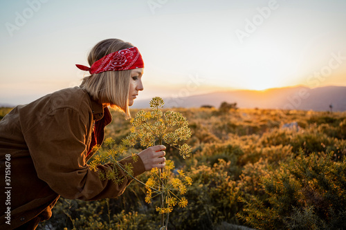 Woman in the countryside smelling at a flower at sunrise photo