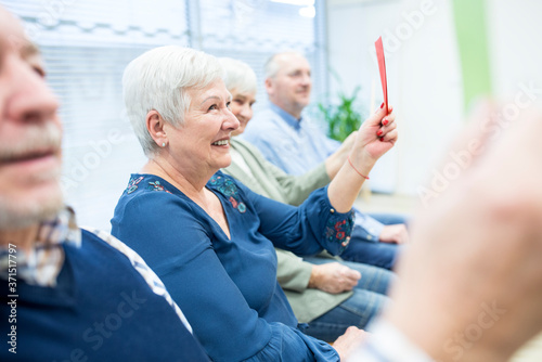 Seniors in retirement home attending group therapy using colorful paper cards photo