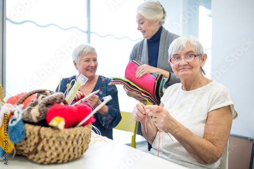Senior women knitting toghether in needlework group of retirement home photo