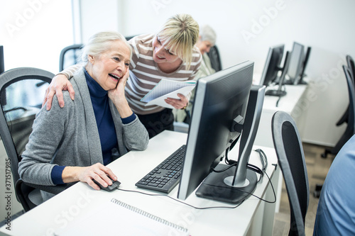 Active seniors attending computer course, intructor giving advice photo