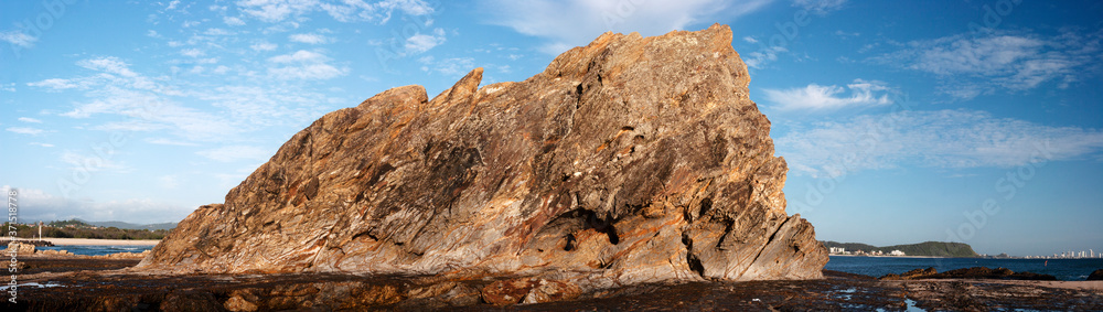 Panoramic shot of a big rock near the coastline