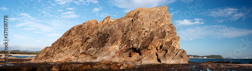 Panoramic shot of a big rock near the coastline