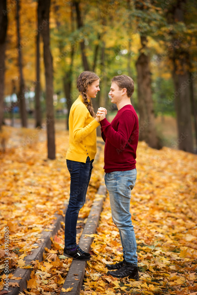 young couple walks in the autumn Park. Orange and yellow leaves around.