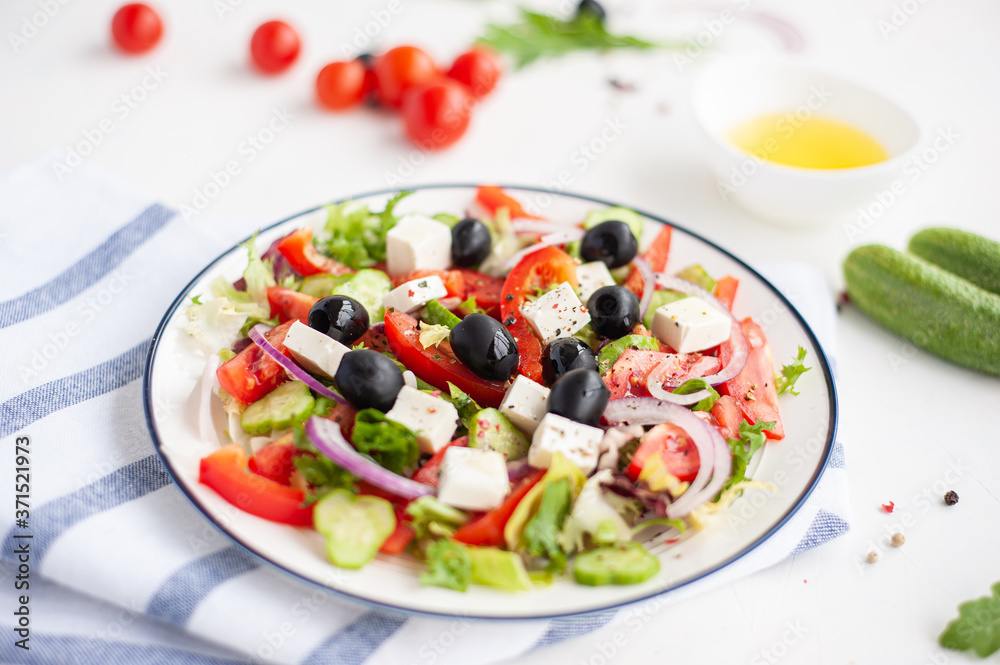 Greek vegetable salad with feta cheese and ingredients from which it is cooked on a white concrete background.