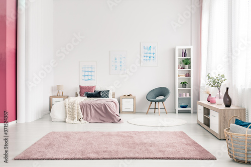 Fashionable open plan bedroom interior with pastel pink design with king size bed and fluffy rug
