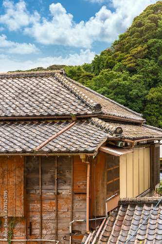 Close-up on a hip roof named yosemunezukuri ornate with decorative Onigawara tile at the end of the ridge and wooden facade named sasarako-shitami of a old traditional Japanese ryokan guesthouse. photo