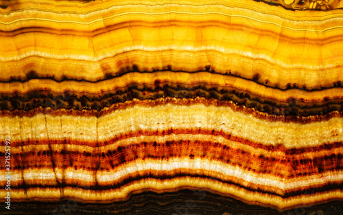 Backlit layered red and yellow marble onyx. Close up detail