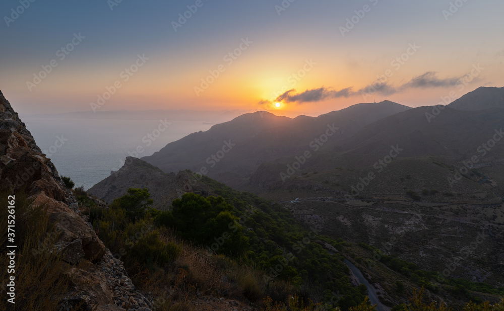 Sunset on the Costa Calida in Spain. The view from the mountain is directed to the south. The Mediterranean is in the haze. In the foreground are deep valleys.