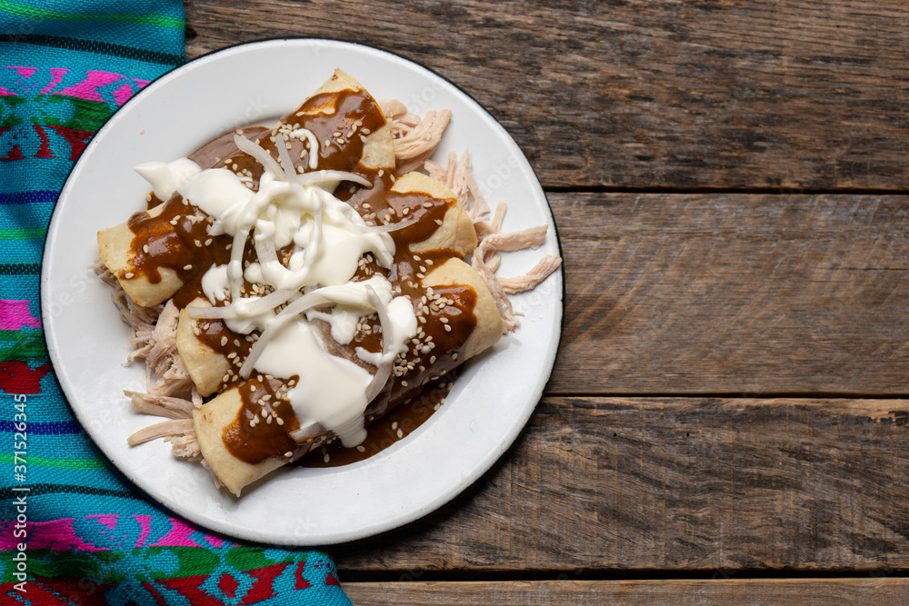 Mexican chicken enchiladas with mole sauce on wooden background Mexican chicken enchiladas with mole sauce on wooden background