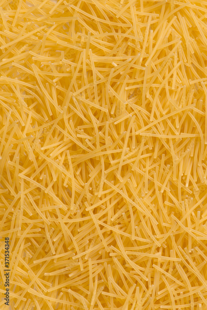 Raw vermicelli pasta background. raw yellow vermicelli is scattered on the table. raw yellow vermicelli scattered randomly on the table. short raw yellow vermicelli for cooking Raw vermicelli pasta background. raw yellow vermicelli is scattered on the table. raw yellow vermicelli scattered randomly on the table. short raw yellow vermicelli for cooking